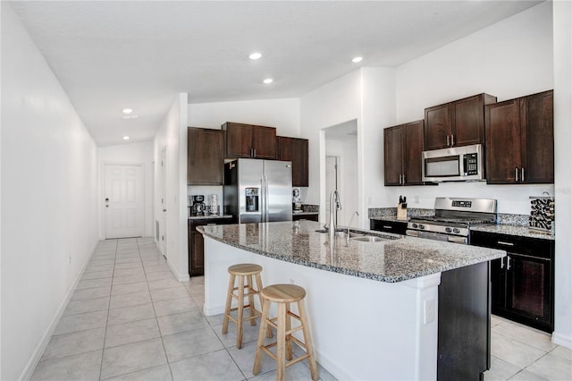 kitchen featuring lofted ceiling, stainless steel appliances, a sink, a kitchen breakfast bar, and an island with sink