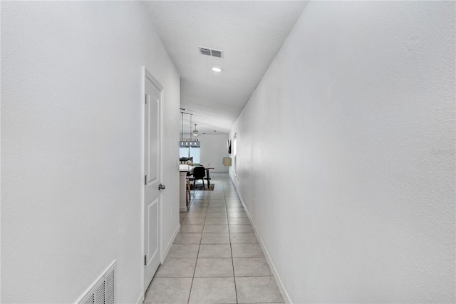 hallway with baseboards, visible vents, and light tile patterned flooring