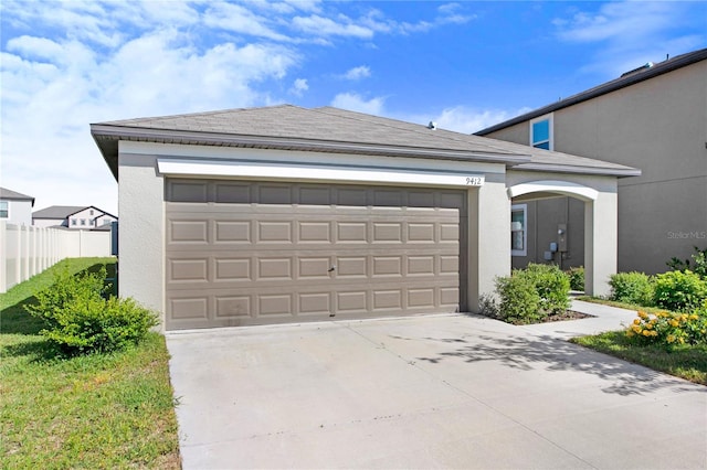 garage featuring driveway and fence