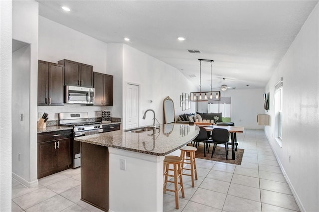 kitchen with light tile patterned floors, appliances with stainless steel finishes, a kitchen breakfast bar, and a sink