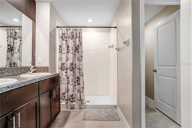 bathroom featuring a stall shower, tile patterned flooring, a sink, and double vanity