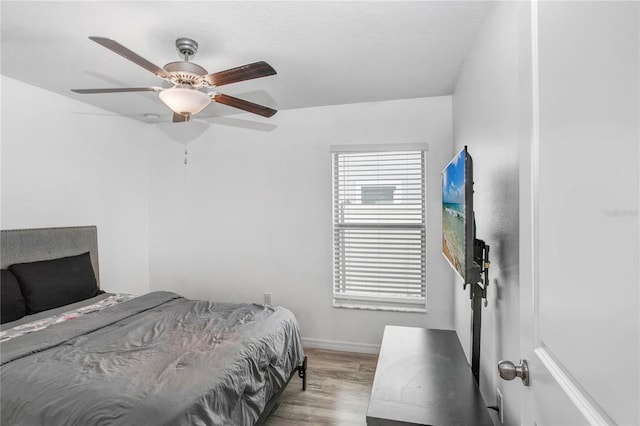 bedroom featuring light wood finished floors, a textured ceiling, baseboards, and a ceiling fan