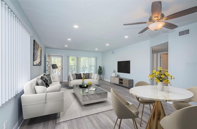 living area featuring baseboards, wood finished floors, visible vents, and recessed lighting