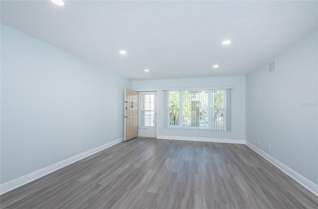 spare room with recessed lighting, visible vents, baseboards, and wood finished floors