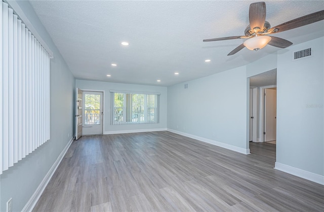 spare room featuring recessed lighting, visible vents, light wood-style flooring, a textured ceiling, and baseboards