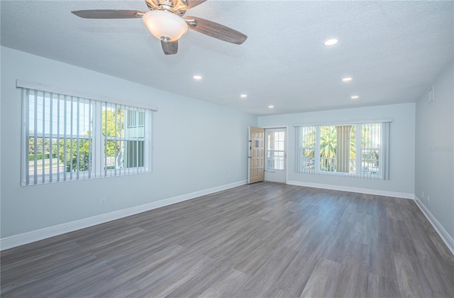 spare room with a textured ceiling, baseboards, and wood finished floors