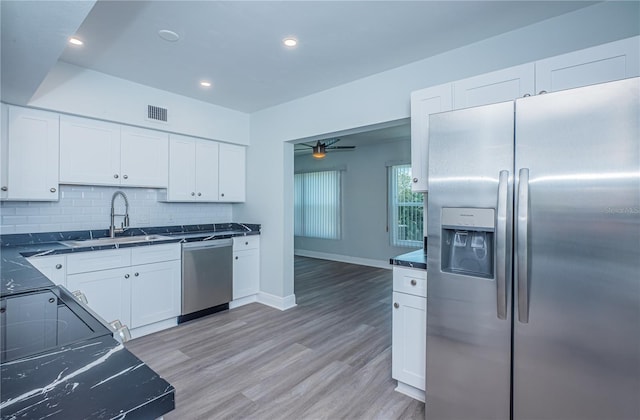 kitchen featuring visible vents, a sink, stainless steel appliances, light wood-type flooring, and backsplash