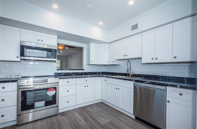 kitchen featuring stainless steel appliances, dark countertops, and a sink