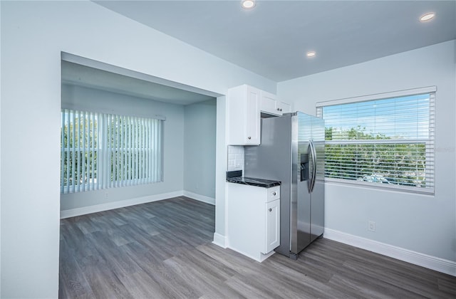 kitchen featuring dark wood-style floors, stainless steel refrigerator with ice dispenser, white cabinetry, and baseboards