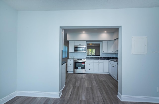 kitchen featuring stainless steel appliances, dark wood-style flooring, baseboards, backsplash, and dark countertops