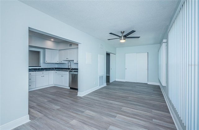 kitchen with visible vents, white cabinets, open floor plan, light wood-style floors, and stainless steel dishwasher