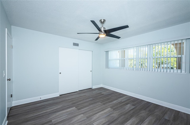 unfurnished bedroom featuring a closet, visible vents, dark wood finished floors, and a textured ceiling