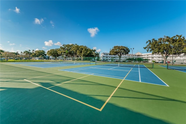 view of tennis court with community basketball court and fence