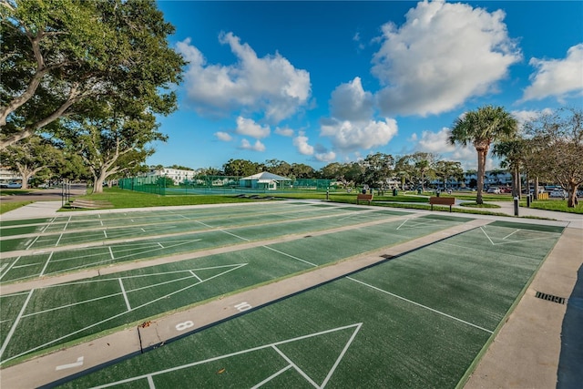 view of home's community with shuffleboard, a lawn, and fence