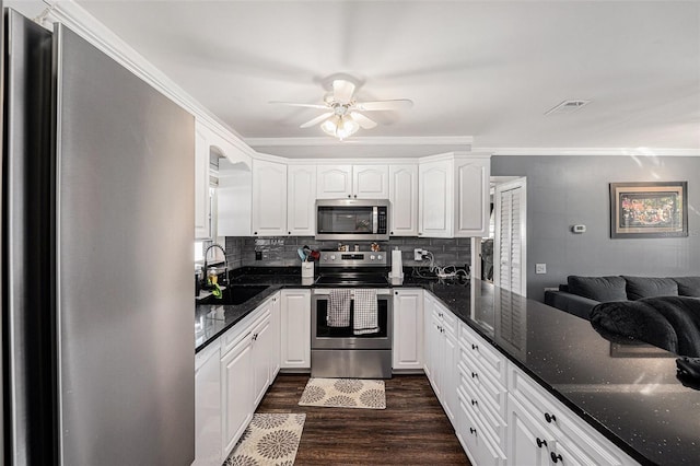 kitchen featuring visible vents, appliances with stainless steel finishes, dark stone countertops, dark wood-type flooring, and a sink