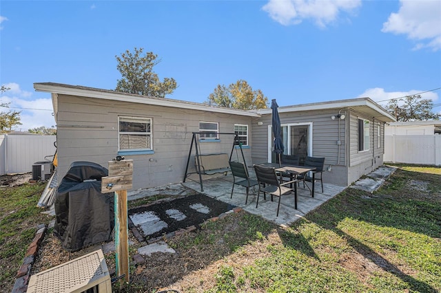 rear view of property with a patio, central AC unit, a lawn, and fence