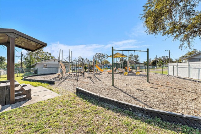 communal playground featuring a lawn and fence