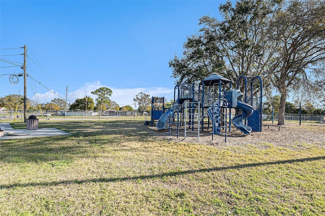 community play area featuring a yard and fence