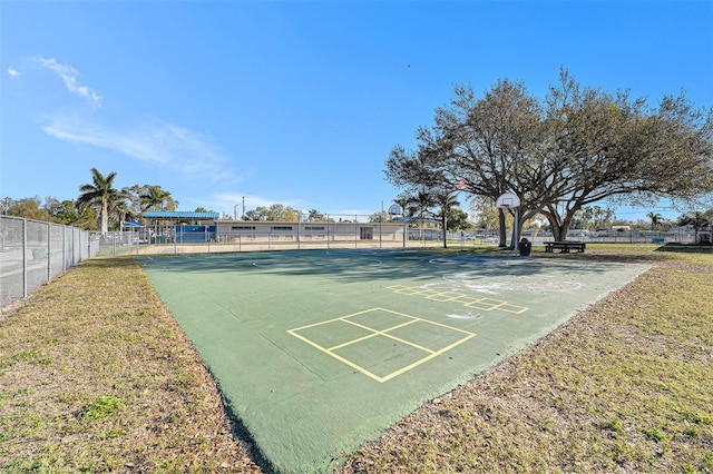 view of property's community featuring community basketball court, a yard, and fence