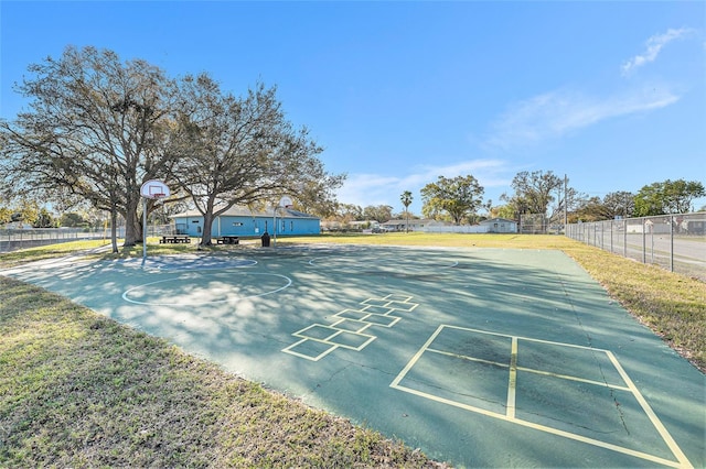 surrounding community featuring community basketball court, fence, and a lawn