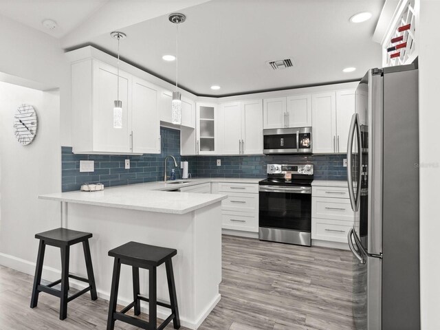 kitchen featuring stainless steel appliances, visible vents, white cabinets, a sink, and a peninsula