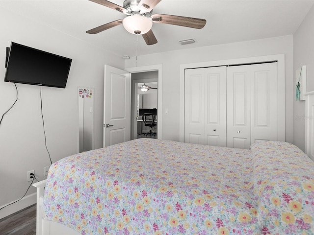 bedroom featuring a ceiling fan, a closet, visible vents, and dark wood finished floors