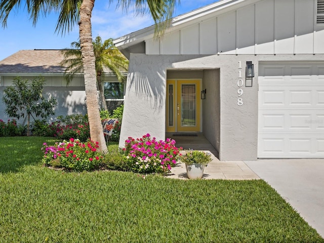 entrance to property with board and batten siding, a lawn, and stucco siding