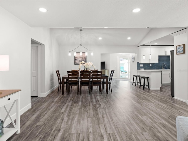 dining area featuring vaulted ceiling, wood finished floors, and recessed lighting