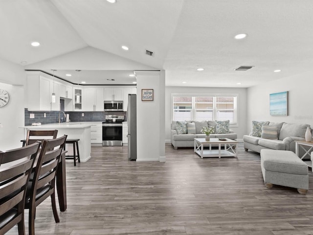 living area featuring recessed lighting, visible vents, vaulted ceiling, and wood finished floors