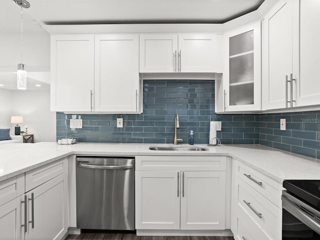 kitchen featuring tasteful backsplash, stainless steel dishwasher, a sink, and white cabinets