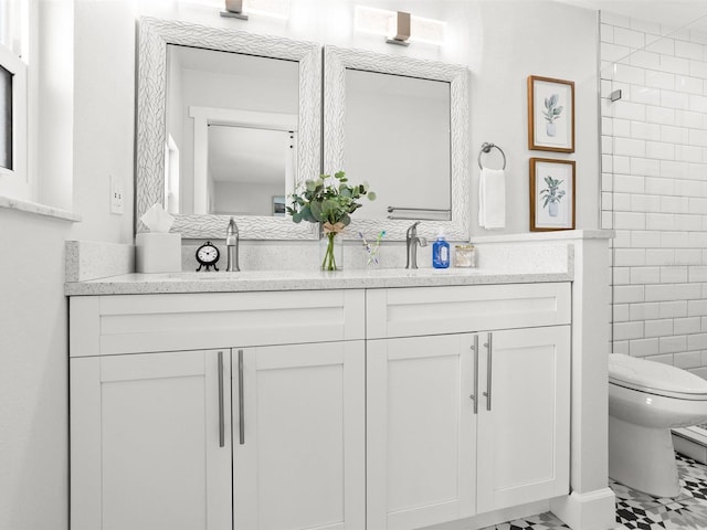 full bathroom with double vanity, tiled shower, toilet, and tile walls