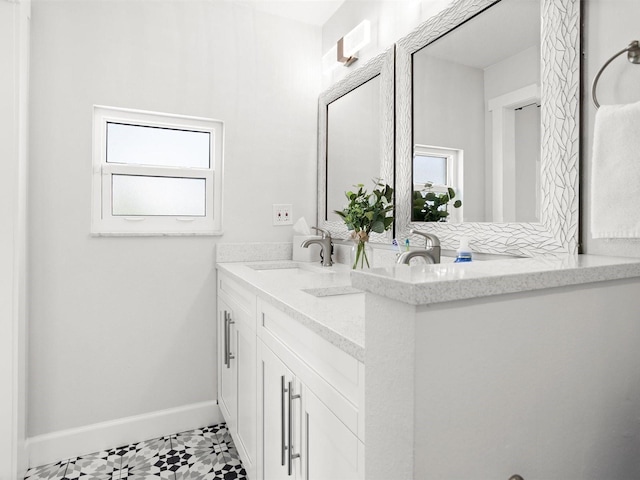 bathroom featuring double vanity, a sink, and baseboards