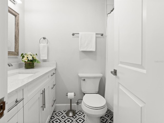 full bathroom with toilet, tile patterned flooring, baseboards, and vanity