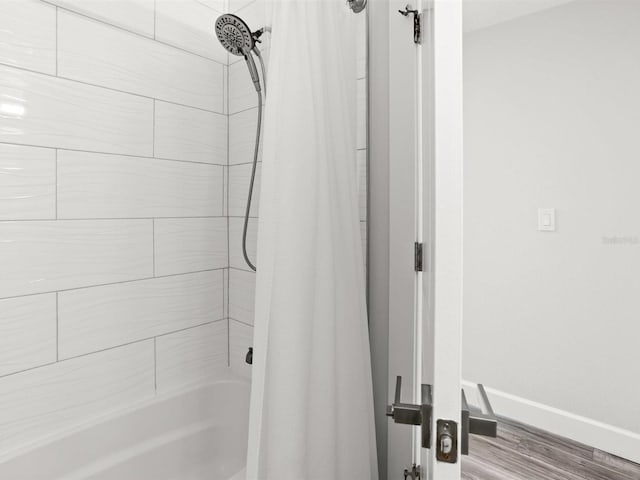 bathroom with baseboards, shower / bath combo with shower curtain, and wood finished floors