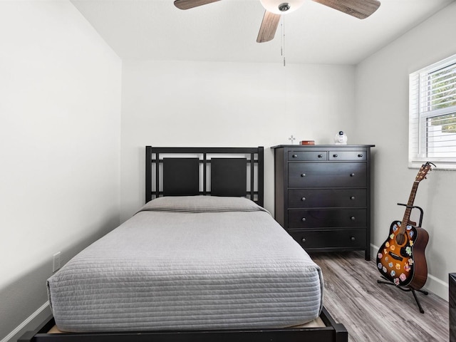 bedroom with a ceiling fan, baseboards, and wood finished floors