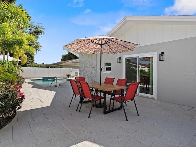 view of patio with a fenced in pool, outdoor dining space, and fence