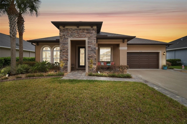 view of front of property featuring stone siding, an attached garage, driveway, and stucco siding