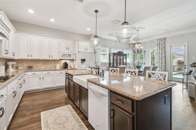 kitchen featuring white appliances, dark brown cabinets, white cabinets, and a sink