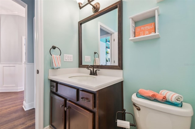 half bathroom with toilet, wood finished floors, and vanity