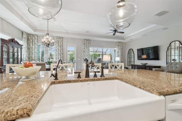 kitchen featuring open floor plan, a tray ceiling, a sink, and visible vents