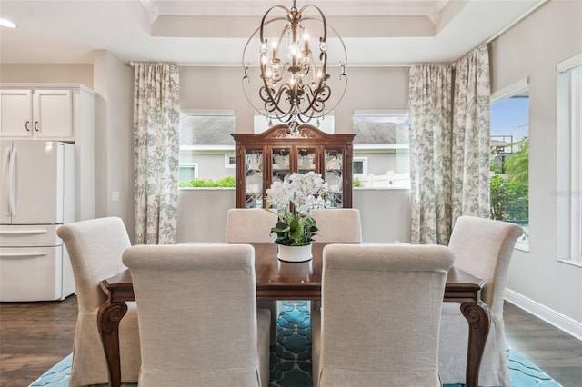 dining area featuring an inviting chandelier, ornamental molding, a raised ceiling, and dark wood-style flooring