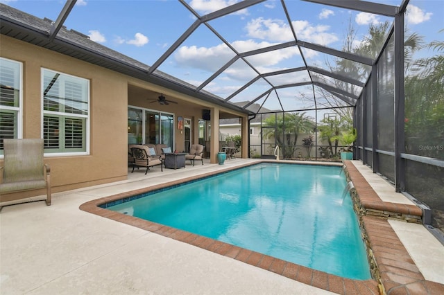 pool featuring glass enclosure, a patio area, and a ceiling fan