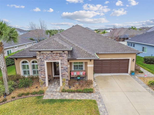 view of front of house with concrete driveway, roof with shingles, an attached garage, and stucco siding