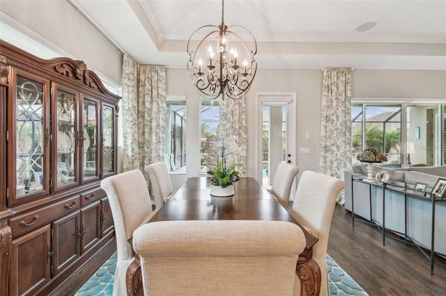 dining room with crown molding, a chandelier, a raised ceiling, and dark wood-style flooring