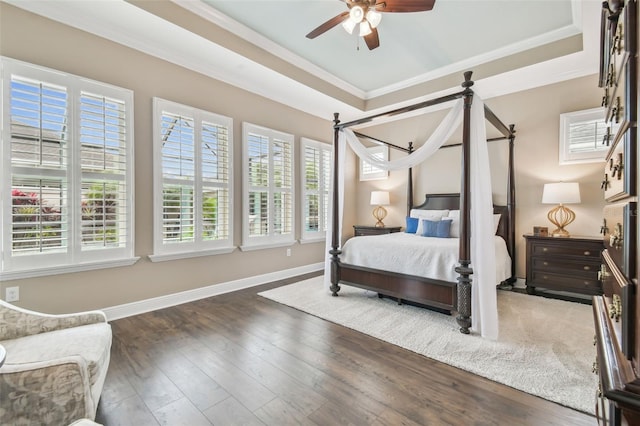 bedroom with baseboards, a tray ceiling, wood-type flooring, and crown molding