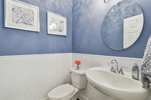 bathroom featuring toilet, a sink, and wainscoting