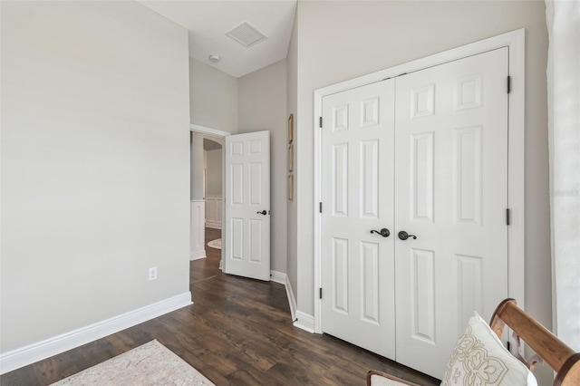 bedroom with dark wood-style floors, baseboards, visible vents, and a closet