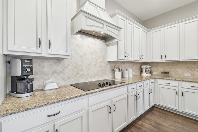 kitchen with black electric stovetop, premium range hood, dark wood-style flooring, white cabinets, and decorative backsplash