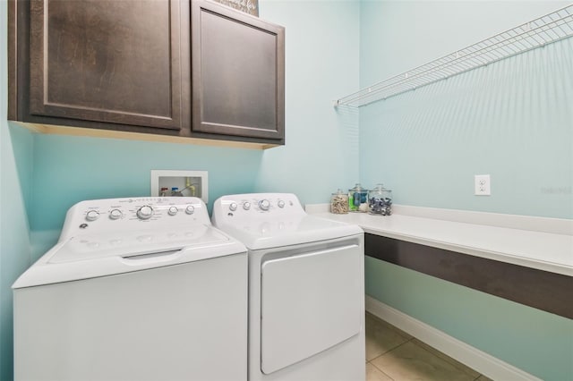 laundry room with baseboards, cabinet space, washing machine and clothes dryer, and light tile patterned floors