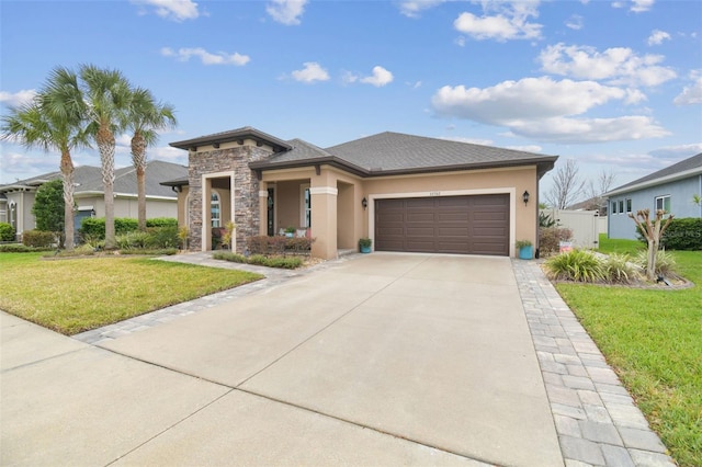 prairie-style home with concrete driveway, stone siding, an attached garage, a front lawn, and stucco siding